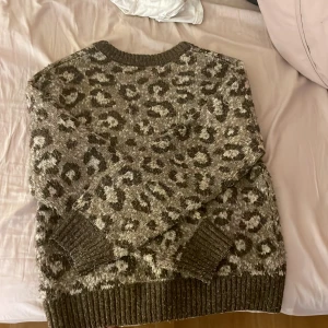 Leopardmönstrad tröja från Primark - Säljer en mysig leopardmönstrad tröja från Primark i bruna och beige toner. Tröjan har långa ärmar och ribbade muddar vid ärmslut och nederkant. Perfekt för en trendig och bekväm look!