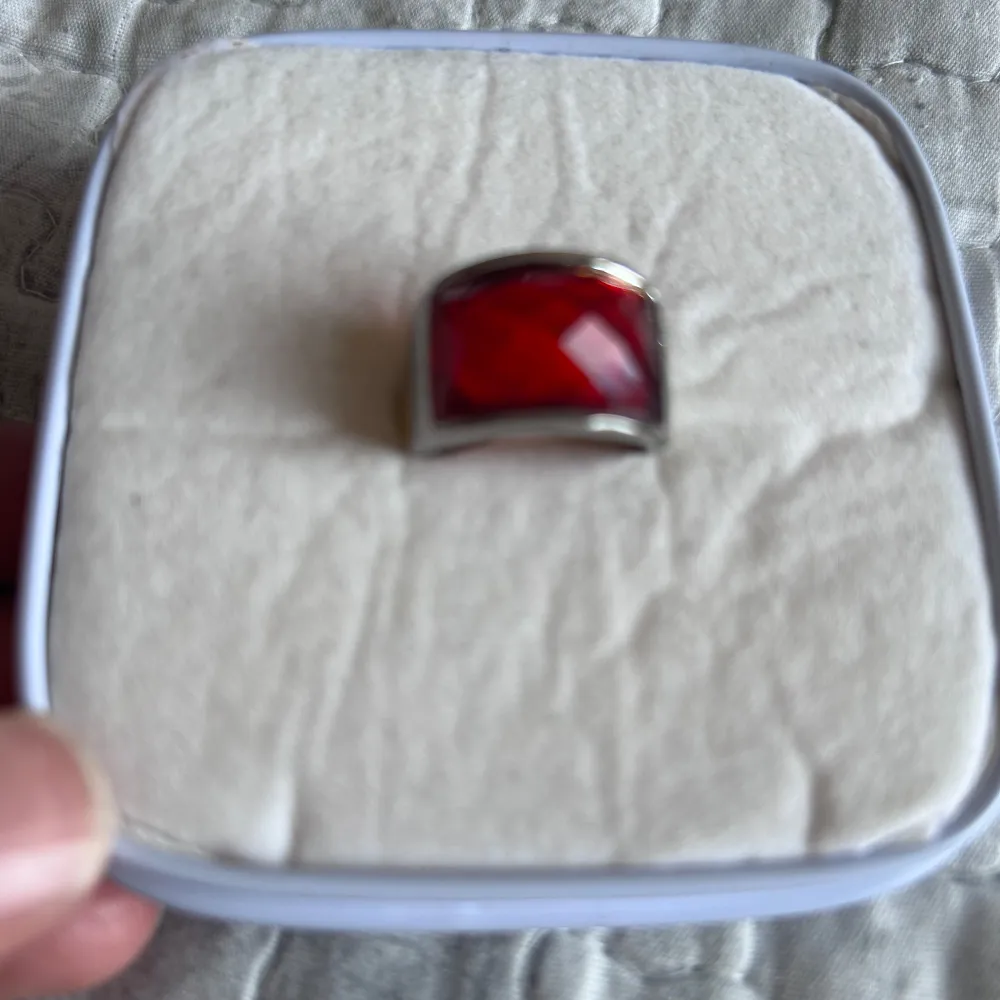 Elegant ring med en stor, fyrkantig röd sten infattad i en silverfärgad ram. Perfekt för att ge en färgklick till din outfit.. Asusteet.