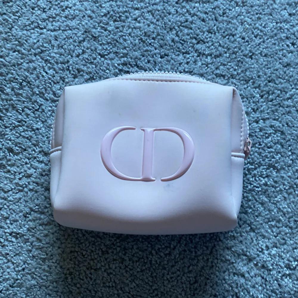 Säljer en söt rosa necessär med en tydlig logotyp på framsidan. Perfekt för att förvara smink eller andra småsaker. Den har en dragkedja upptill för säker förvaring.. Laukut & Käsilaukut.