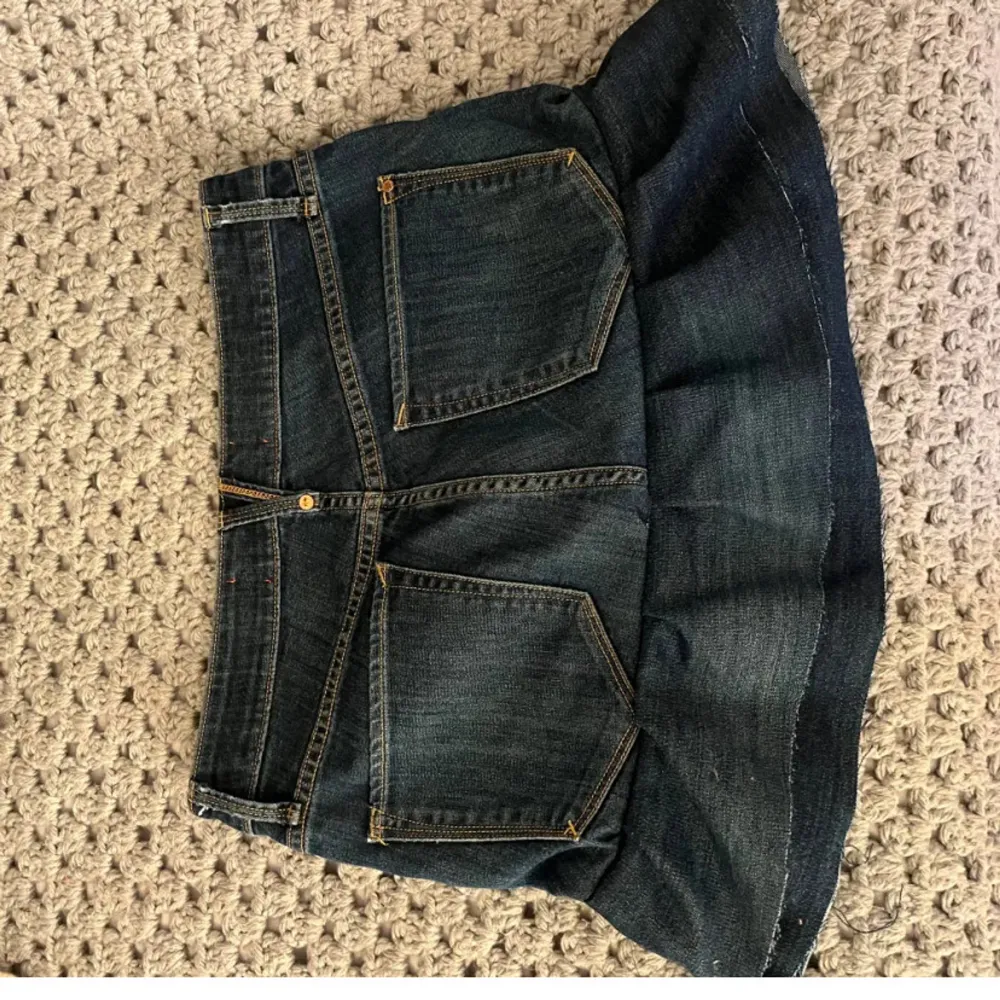 Säljer en mörkblå jeanskjol från marc jacobs med volang nertill (sydd). Kjolen har klassiska jeansfickor fram och bak samt dragkedja och knapp framtill. Perfekt för dig som gillar en tuff och trendig stil.. Hameet.