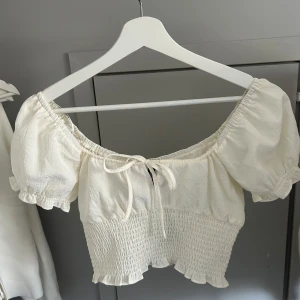 Vit croppad blus med puffärmar från H&M - Säljer en så söt croppad blus från H&M med puffiga korta ärmar och knyt framtill. Jag köpte den för några år sen men den kom aldrig till användning för att den var lite för liten för mig🤍Perfekt till våren och sommaren☀️