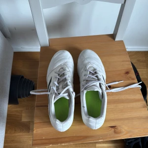 Vita Adidas Copa fotbollsskor - Säljer ett par vita Adidas Copa fotbollsskor. Som är 2 år gamla, har använt de en period men de är som nya. Köpte de för 1600kr i 2023. Men säljer de för 700kr