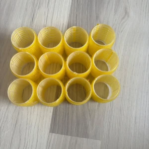 Gula hårspolar för styling - Säljer ett set med tolv gula hårspolar i plast och kardborre. Perfekta för att skapa volym och lockar i håret utan värme. Lätta att använda och passar de flesta hårtyper. Färgen är klargul och varje spole är cylindrisk.