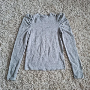 Grå tröja från Zara - Ljusgrå långärmad tröja från Zara med puffade axlar och dekorativa pärlor på ärmarna!