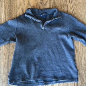  Polo Ralph Lauren half zip  - Säljer en stilren grå tröja från Polo Ralph Lauren half zip. Tröjan har långa ärmar och är perfekt för en avslappnad stil och perfekta till sommarkvällar. Storlek 164-170