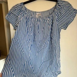 Blåvit randig blus från Rainbow - Säljer en söt blus från Rainbow med blå och vita ränder. Blusen har korta ärmar och en rundad, lite rynkad halsringning. Perfekt för varma dagar och enkel att matcha med jeans eller kjol. 38, passsr både S & M