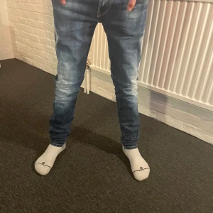 Replay anbass hyperflex - Snygga blå jeans från Replay med en klassisk femficksdesign och ljusa tvättade detaljer. De har en knappgylf och är tillverkade i ett slitstarkt denimtyg. Perfekta för en avslappnad stil. Storlek är 28/32!!!