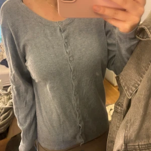 Ljusblå kofta med knappar - Säljer en ljusblå kofta med knappar framtill. Den har en rund halsringning och långa ärmar, perfekt för en avslappnad stil. Koftan är mjuk och bekväm. Man blir varken för kall eller för varm i den. Passar om man har storlek xs/s. 