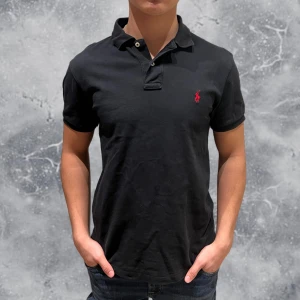 Ralph Lauren Piké Svart - •Ralph Lauren Piké svart. Skick: 8/10, Inga skador! Storlek: M, fits S (slim fit). Modell: 173 cm, 63 kg. Sitter bra på modellen på bild som vanligtvis bär XS/S! Authentic: ✅. Hör av dig vid frågor eller funderingar, mvh Hessler’s;)
