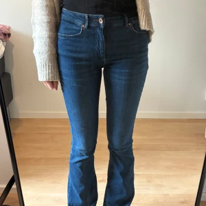 Blå bootcut jeans från ONLY - Säljer ett par klassiska blå bootcut jeans från ONLY. Jeansen har medel hög midja, fem fickor och stängs med dragkedja och knapp. Snygg passform som sitter tight upptill och släpper ut vid benslutet.