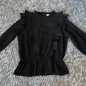 Svart blus med volangdetaljer - Fin volangblus i svart, från lindex i storlek 146❤️ Hör av dig om du är intresserad!! Pris kan diskuteras :)