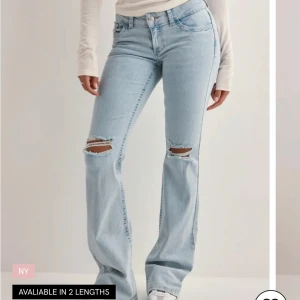 Ljusblå bootcut jeans med slitningar - Jätte fina ljusblå jeans med bootcut-modell och slitna hål över knäna. Säljer ”Nelly jeansen”, bra skick. Lite slitna längst ner vid hälarna och trådarna vid hålen är lite mer öppna. Perfekta för en avslappnad och trendig look. Pris går att diskuteras!!