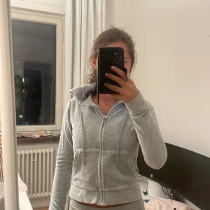 juciy kofta grå - Säljer en ljusgrå hoodie från Juicy Couture med dragkedja framtill, huva och snörning. snygg är den