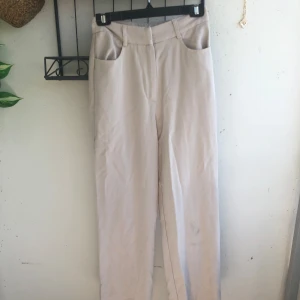 Beiga raka kostymbyxor  -  Beiga kostymbyxor med raka ben, hög midja och klassiska fickor både fram och bak. Byxorna har hysk- och hakstängning samt dragkedja. Jag är 168cm och domhär sitter jätte bra på längden tycker jag dom är till sko kanten (sneakers)