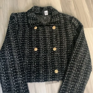 Svartvit rutig cardigan jacka med guldknappar - Snygg svartvit rutig cardigan jacka med coola guldknappar framtill. Jackan har en boxig, croppad passform och är långärmad. Materialet är stickat och ger en mjuk och trendig känsla. Perfekt för dig som vill ha en chic och stilren look. Pris kan diskuteras 