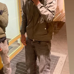 Monclear grimpeurs  windbreaker - Snygg grön vindjacka från Moncler med huva och dragsko, klassisk logga på ärmen och dragkedja framtill. Jackan har två fickor med tryckknappar och elastiska muddar vid ärmslut och midja. Perfekt för dig som gillar stilren och sportig look.