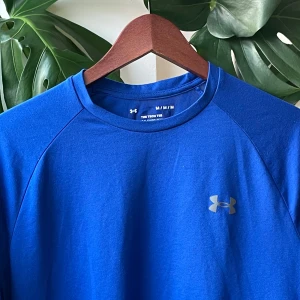 Under Armour Tech Tee t-shirt - Snygg blå t-shirt från Under Armour med klassisk logga på bröstet. Modellen är kortärmad och har en sportig passform, perfekt för träning. Tillverkad i ett lätt och funktionellt syntetmaterial som andas.