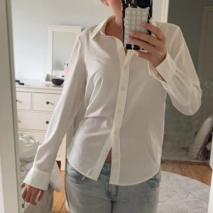 Vit klassisk skjorta med knappar - Säljer en stilren vit skjorta med klassisk krage och knäppning framtill. Skjortan har lång ärm och är tillverkad i ett tunt, mjukt material som känns skönt mot huden. Perfekt till jeans eller kostymbyxor. Säljer då jag inte andvänder !!!💓💓💓