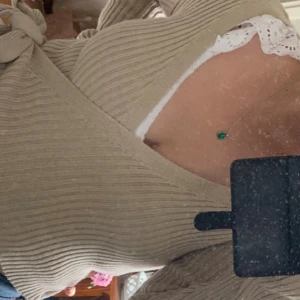 Beige ribbad omlottopp med knyt - Helt ny, oanvänd (lapp är kvar). Trendig beige omlottopp med ribbad struktur och knyt i sidan. Toppen har lång ärm och en croppad passform som visar lite midja. Perfekt för dig som gillar en stilren men ändå cool look. Från NA-KD, och den finns inte längre att köpa på NA-KD. 