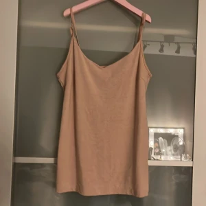 Beige linnetopp från 157, storlek L - Säljer en enkel och stilren beige linnetopp från 157 i storlek L. Toppen har tunna axelband och en avslappnad passform. Materialet är en mjuk mix av bomull, polyester och elastan som gör den skön att bära. Perfekt för varma dagar eller lager på lager.