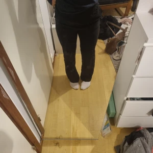 Svarta mjukisbyxor med resårmidja - Svarta mjukisbyxor med resår i midjan och raka ben. Sköna och avslappnade, perfekta för chill eller hemmadagar. Byxorna har fickor på sidorna och är gjorda i mjukt material som känns bekvämt mot huden.