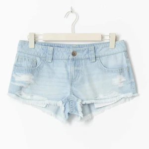 Ljusblå jeansshorts med slitningar - Snygga ljusblå jeansshorts med slitna detaljer och fransig kant. Köpte fel storlek men dem sitter jätte bra annars och älskar färgen! Har aldrig använt de. Klassisk femficksmodell med låg midja och coola slitningar framtill. Baksidan har dekorativa sömmar på fickorna. Perfekta för varma dagar när du vill ha en avslappnad look. Skriv om du vill ha fler bilder tex hur dem sitter på!❤️