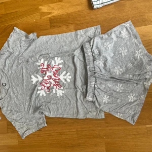 Grå shorts med snöflingor XS - Mysiga grå shorts från Cubus i storlek XS, dekorerade med vita snöflingor över hela tyget. De har elastisk midja och är gjorda i mjuk bomull, perfekta för chill dagar hemma.