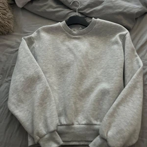 Grå basic tröja från Gina  - Enkel och stilren grå tröja från Gina med rund halsringning och ribbade muddar vid ärmslut och midja. Mjuk och skön, passar till allt. Använd max 3 gånger. 