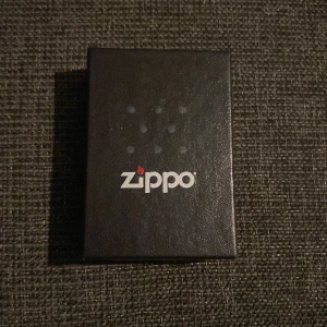 Zippo tändare - Det här är ingen bok, utan en Zippo-tändare med coolt Santa Cruz-motiv. Perfekt för dig som gillar unika accessoarer eller samlar på Zippo-tändare. Tändaren levereras i originalförpackning och har ett färgstarkt, detaljerat tryck som sticker ut 