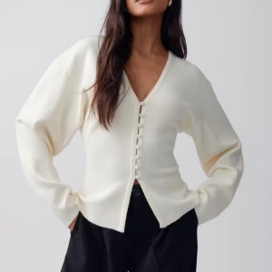 Shaped knitted cardigan från Gina tricot  - Stilren vit kofta med v-ringad hals och snygga knappar framtill. Tröjan har långärmad design och en rak, något loose passform. Perfekt att slänga över en topp för en clean och enkel look.