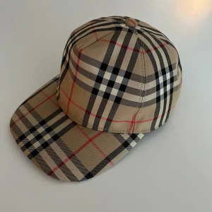 Burberry keps - Snygg keps från Burberry med deras klassiska mönster. Kepsen är storlek L men går att justera. Den har använts några gånger men det är inget som syns. Hör av er om ni har fler frågor 