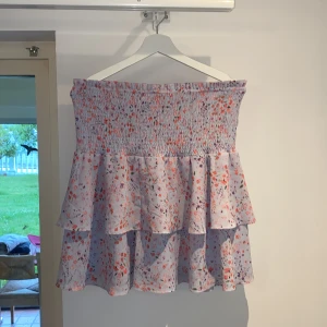 Ljuslila blommig volangkjol från Cubus - Kjol i ljuslila med små blommor i rosa, rött och lila. Kjolen har volanger som ger en flowy känsla.