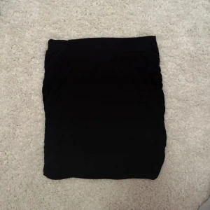 Svart tight kortkjol - Enkel svart tight kortkjol med rak passform. Perfekt att matcha med en oversized hoodie eller crop top. Kjolen är basic och funkar till många olika stilar.