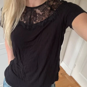 Svart spets topp  - Supersnygg svart topp med offshoulder och bred spets upptill. Toppen har korta ärmar och en figurnära passform som ger en stilren look. Perfekt för dig som gillar en enkel men elegant stil.