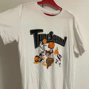 Vit Tune Squad t-shirt Looney Tunes - Vit t-shirt med Tune Squad-tryck och Looney Tunes-karaktärer som Bugs Bunny, Daffy Duck, Taz, Tweety och Sylvester. Klassisk passform med rund hals och korta ärmar. Perfekt för dig som älskar Space Jam och tecknade motiv. Perfekt skick aldrig tagen på, helt ny 