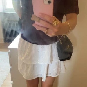Vit volangkjol från Gina Tricot - Supersöt vit kortkjol från Gina Tricot med broderade blommor och volanger. Kjolen har smock i midjan för en bekväm passform och är gjord i luftig bomull. Den är i barnstolek 170💕