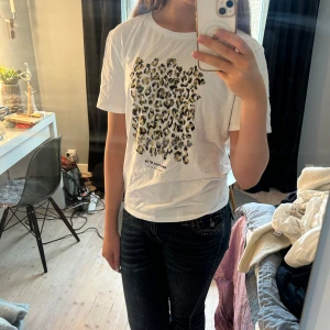 leopardmönstrad t-shirt Zara - Vit t-shirt från Zara med coolt leopardmönster i svart och guld på bröstet. Klassisk rund halsringning och korta ärmar. Skön bomullskvalitet och avslappnad passform. Perfekt för dig som vill sticka ut lite extra.