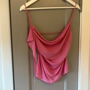 Rosa omlottopp från Pull&Bear - Säljer en rosa omlottopp från Pull&Bear i storlek S. Toppen har tunna axelband, och ett tunt band i ryggen. Materialet är lätt och flowy, perfekt för varma dagar. Snygg att styla med jeans eller kjol! Har en liten slinga på den som har gått sönder annat sjättefin! Säljer då den aldrig kommer till andvänding! Hör av er vid frågor❤️