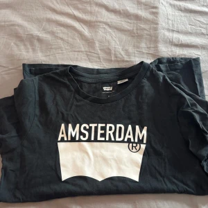 Svart Levi's Amsterdam t-shirt XS - Svart t-shirt från Levi's i bomull med vit Amsterdam-tryck framtill. Klassisk rund hals och korta ärmar. Storlek XS