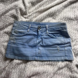 Lågmidjad Ljusblå jeanskjol med slitningar - Lågmidjad jeanskjol , finns vissa fläckar men syns inget när man bär den på! 