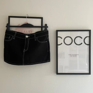 Svart jeanskjol från H&M  - Svart kort jeanskjol från H&M Divided med vita kontrastsömmar, klassiska fickor fram och bak samt silverfärgade knappar. Tillverkad i 100% bomull för en skön och cool känsla. Perfekt till sneakers eller boots. Skriv om du undrar något 🩷