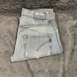 Dondup jeans - Säljer ett par ljusblå dondup jenans  i bra skick med coola slitningar för en avslappnad look. Perfekta för vardagsbruk och kan stylas med en t-shirt eller hoodie. De har en klassisk femficksdesign och är gjorda i ett bekvämt denimtyg. Bara att höra av sig vid frågor och funderingar! 