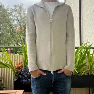 Beige ribbad kofta från Ljung - Säljer en stilren beige ribbad kofta från Ljung by Marcus Larsson i storlek S. Koftan har hel dragkedja framtill, hög krage och är långärmad. Perfekt för lager-på-lager och passar till jeans eller chinos.