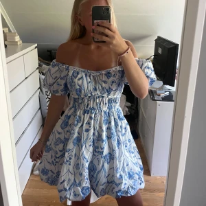 Blommig offshoulder ballongklänning - Superfin vit och blå klänning med blommigt mönster från hm. Kan både ha offsholder men även vanligt. Den är helt oanvänd med lappen kvar💓💓