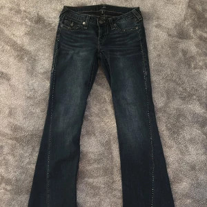 Joey Trueys med stenar - Super fina jeans från True Religion i modellen joey, med stenar på jeansen sidor. I en jättefin färg och i super skick! Endast använda en gång💖 i strl 26