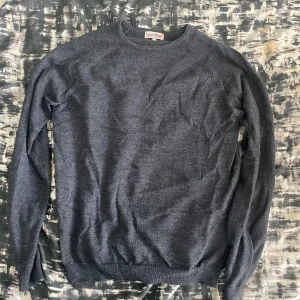 Mörkblå stickad tröja Iconic Sport - Mörkblå stickad tröja från Iconic Sport i enkel och stilren design. Tröjan har rund halsringning, långa ärmar och ribbade muddar vid ärmslut och nederkant. Perfekt för lager-på-lager under kyliga dagar.