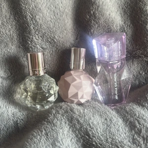 Ariana Grande parfymtrio - Tre snygga Ariana Grande parfymer i olika flaskor: en klar diamantformad, en matt ljusrosa med geometriskt mönster och en hög, lila transparent flaska. Alla har coola former och silverdetaljer, perfekta för parfymhyllan. Tycker dom luktar super gott men har redan dom stora så behöver inte dom små dom är knappt använda. Köpte dom från Lyko för ungefär 550kr. Skriv vid mer frågor.
