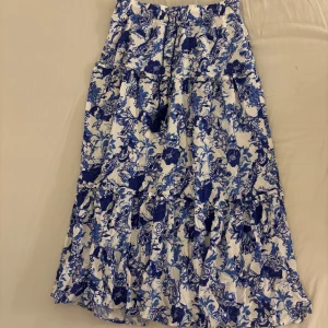 Blommig långkjol från Holly & Whyte, by Lindex  - Supersöt långkjol från Holly & Whyte med blått och vitt blommönster som jag bara har använt fåtal gånger. Kjolen har volanger och en dragsko med tofsar i midjan. Lätt och luftig, passar perfekt till varma dagar.