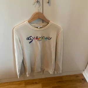 Beige Givenchy sweatshirt med broderi - Säljer en vit sweatshirt från Givenchy med färgglatt broderat logotyp på bröstet. Tröjan har rund halsringning och långa ärmar. Perfekt för dig som vill ha en clean men ändå färgstark look. Passar till allt och är superbekväm. Ny pris mellan 5-7 tusen men säljer denna billigt för att den är andvänd rätt så mycket och finns täcken på andvändnig
