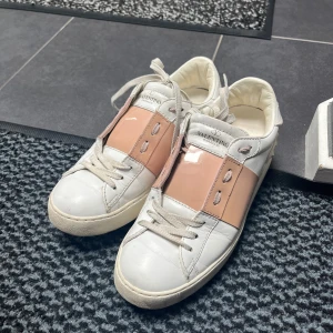 Valentino Garavani Open sneakers vit/rosa - Snygga Valentino Garavani Open sneakers i vitt skinn med bred rosa panel över vristen. Köpta från Farfetch för 1 år sedan och mycket sparsamt använda. Nypris 7280 kr mitt pris 2700. Box tillkommer🪭🌸💗